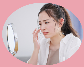 お顔の肌で悩んでいる女性が鏡をのぞいて困っている画像